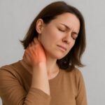 Office worker experiencing neck and shoulder pain while working on a laptop due to poor posture and prolonged screen time