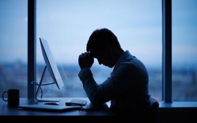 Young office professional sitting with poor posture and experiencing neck and back pain while working on a laptop.
