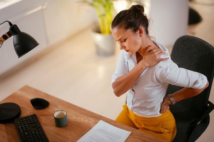 Young office professional suffering from neck and back pain due to prolonged sitting and poor posture at work