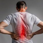 Office professional experiencing lower back pain while sitting at a desk due to prolonged working hours
